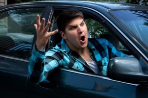 An irritated young man driving a vehicle is expressing his road rage.
